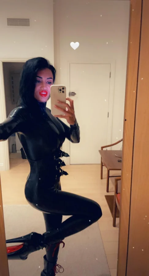 Mistress Elizabeth taking a selfie wearing a latex bodysuit