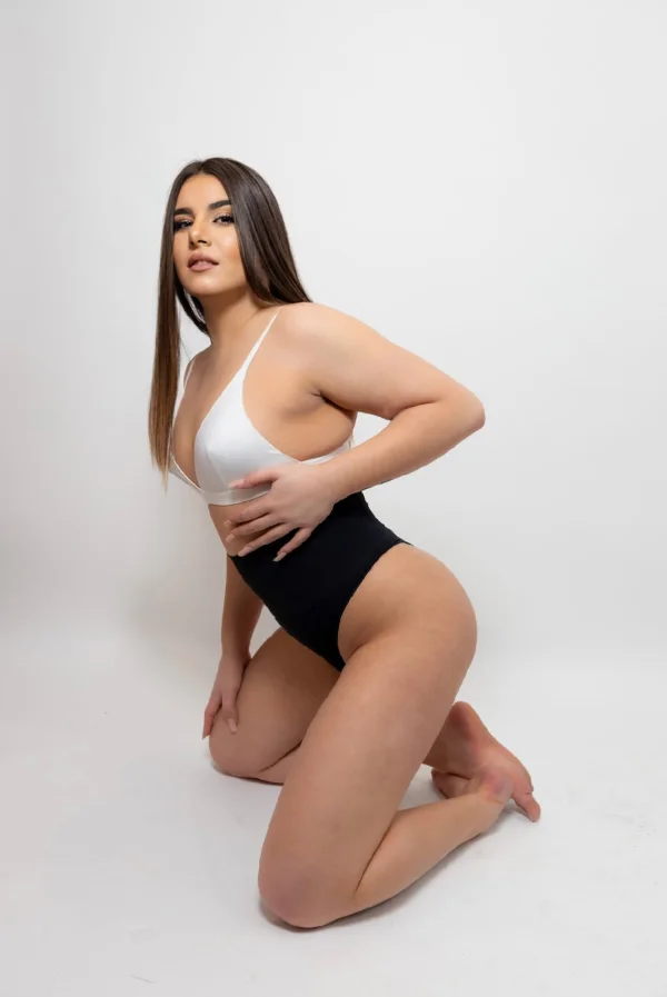 Larisss is kneeling down and has one hand on her boob 