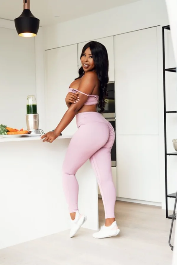 A curvy ebony London escort is pictured wearing pink tight leggings 