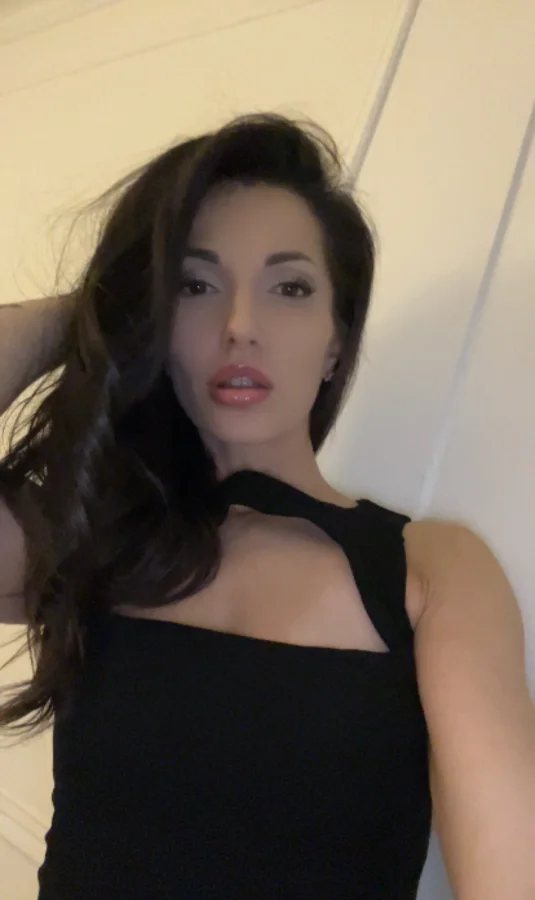 Selfie of a brunette Russian female escort wearing a black dress 