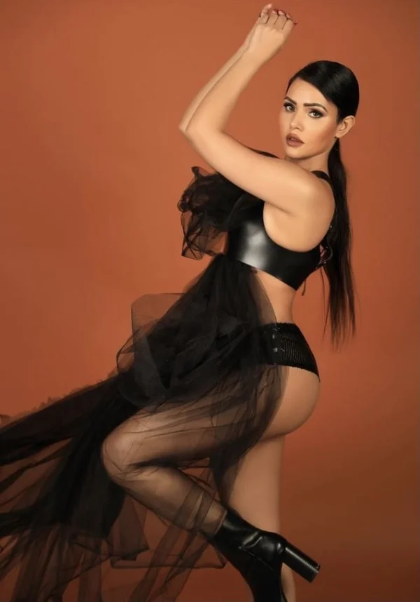 Anitta is holding onto a black silk cloth 