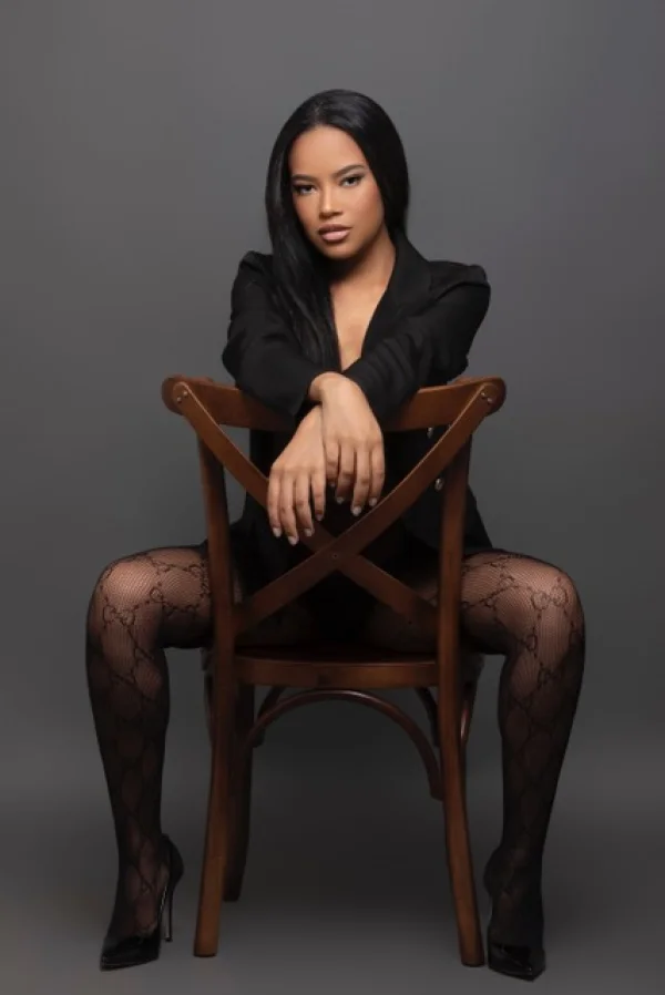 Brazilian ebony escort Cameo is straddling a chair 