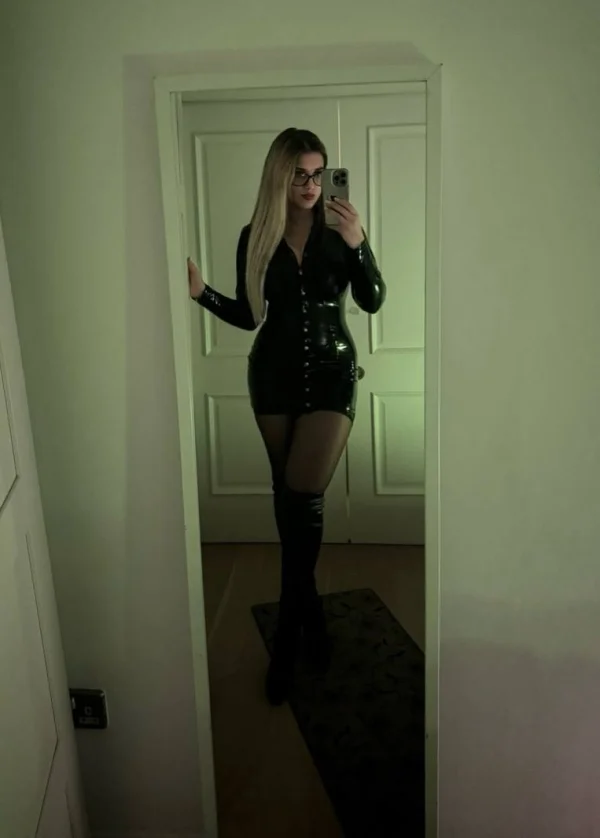 Selfie of a blonde London dominatrix wearing a black latex dress 